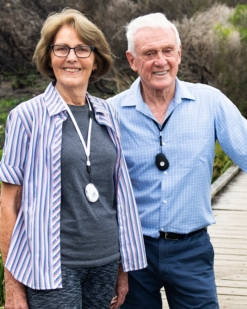 Senior couple wearing LiveLife personal emergency alarm pendants with fall detection