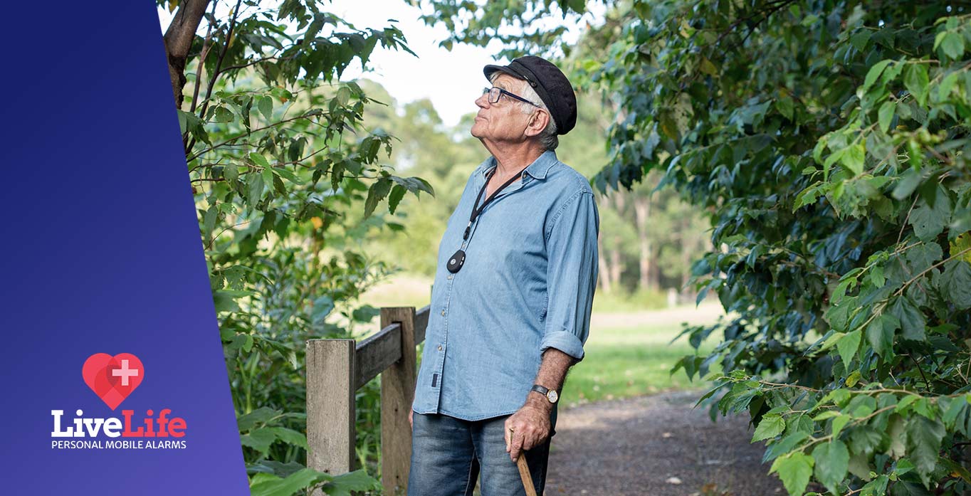 man walking through park wearing a live life alarm pendant